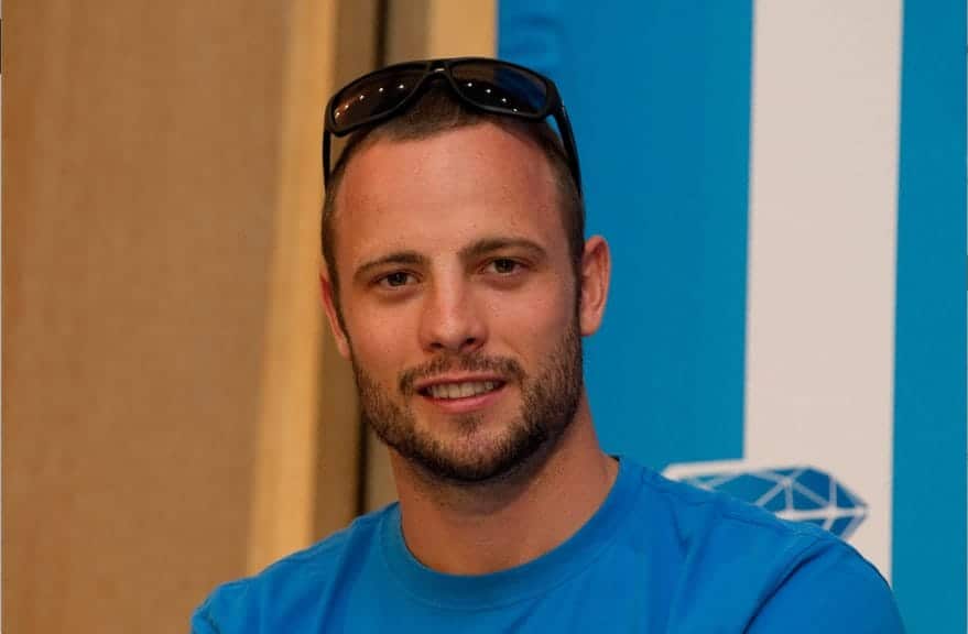 Photo of Oscar Smiling from shoulders up. He is wearing black sunglasses and a blue shirt.